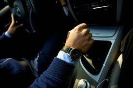 man wearing a navy blue suit driving a bmw with a nice watch